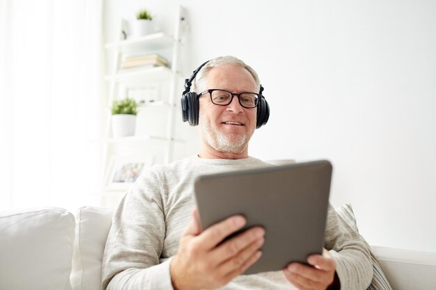 tecnologia, persone, stile di vita e concetto di apprendimento a distanza - uomo anziano felice con computer tablet pc e cuffie che ascoltano musica a casa