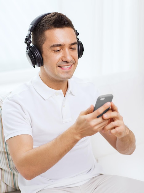 tecnologia, persone, stile di vita e concetto di apprendimento a distanza - uomo felice con smartphone e cuffie che ascolta musica a casa