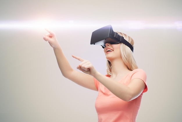 tecnologia, realtà virtuale, intrattenimento e concetto di persone - giovane donna felice con cuffie per realtà virtuale o occhiali 3d su sfondo grigio e luce laser