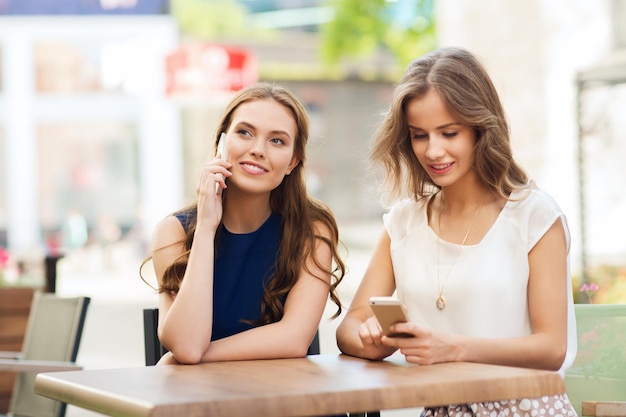 tecnologia, stile di vita, amicizia, comunicazione e concetto di persone - giovani donne felici o ragazze adolescenti con smartphone al bar all'aperto