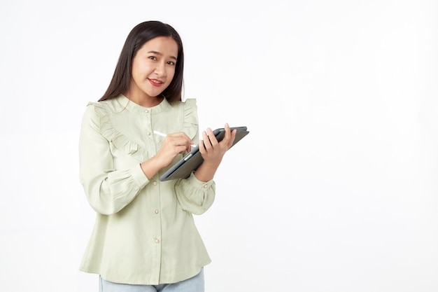 Tecnologia wireless. Bella giovane donna asiatica che tiene compressa digitale e che guarda l'obbiettivo con il sorriso mentre levandosi in piedi isolato su fondo bianco.