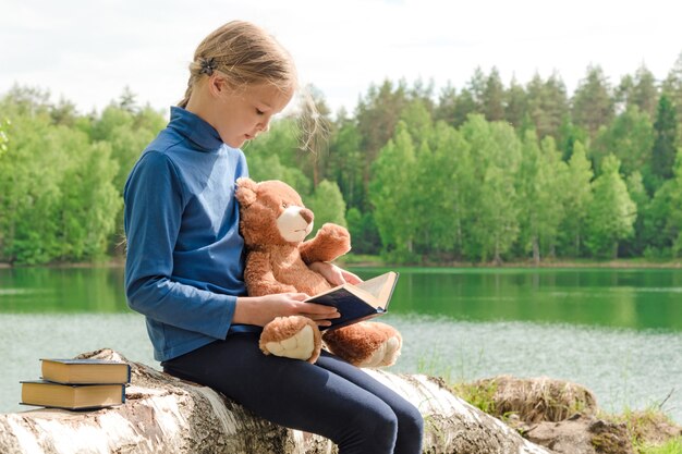 Teddy Bear e la piccola ragazza sveglia hanno letto il libro sul picnic in natura dell'estate.