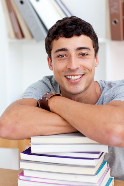 Teeenager sorridente che studia molti libri