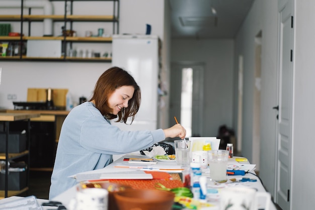 Teengirl ragazza fa un'applicazione di carta di carta colorata con il pupazzo di neve Il concetto di creatività La ragazza fa artigianato carta da cartolina carta multicolore per la creatività Lavorare da casa Hobby