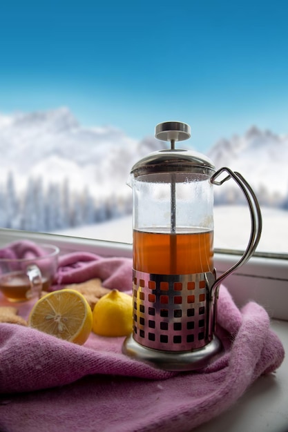 Teiera con tè e biscotti vicino alla finestra invernale