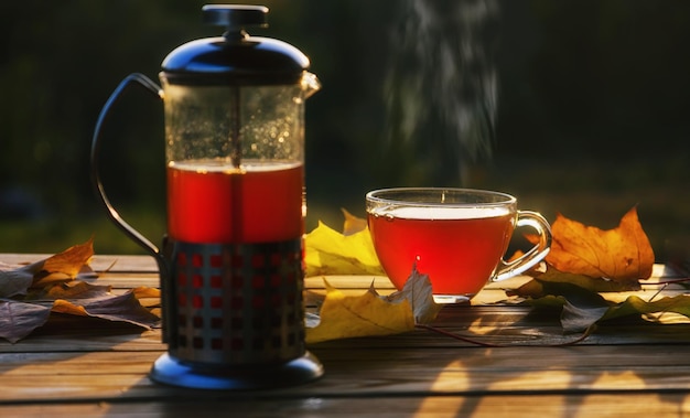 Teiera con tè e tazza vicino alle foglie d'autunno