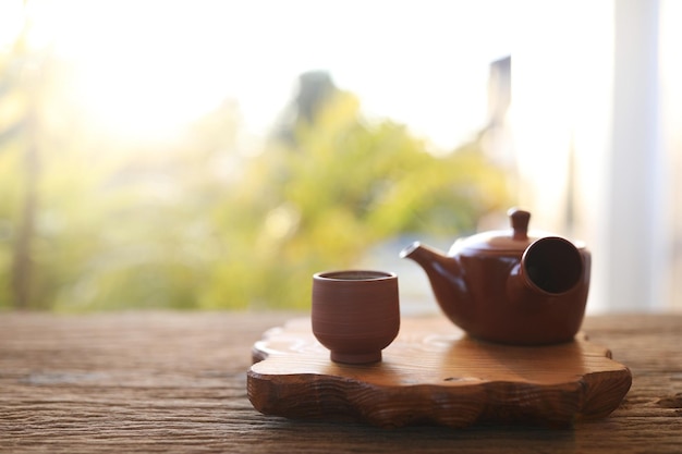 Teiera di terracotta e tazza da tè sul vassoio di legno