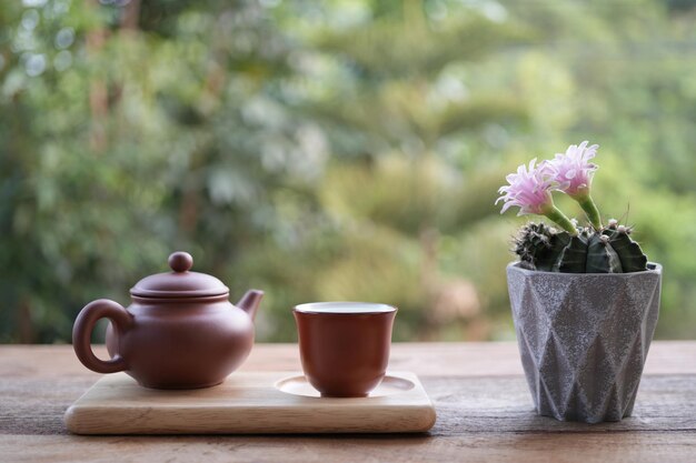 Teiera di terracotta e tazza di tè e fiore di cactus rosa su un tavolo di legno