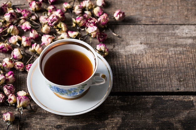 Teiera e tazza d&#39;annata con i fiori di fioritura del tè su di legno