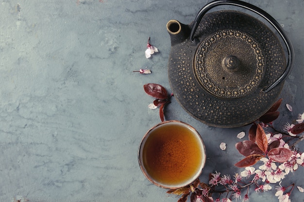 Teiera e tazza di tè con ramo di fiori