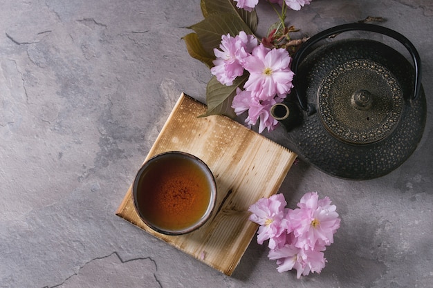 Teiera e tazza di tè con ramo di fiori