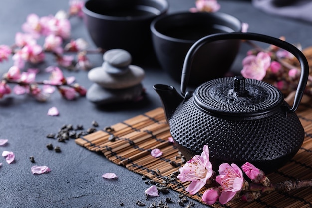 Teiera e tazze da tè con rami di mandorlo in fiore
