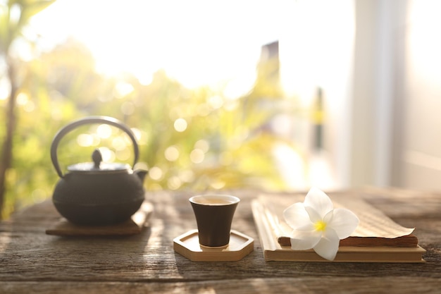 Teiera Eathenware e tazza da tè e fiore sulla tavola di legno