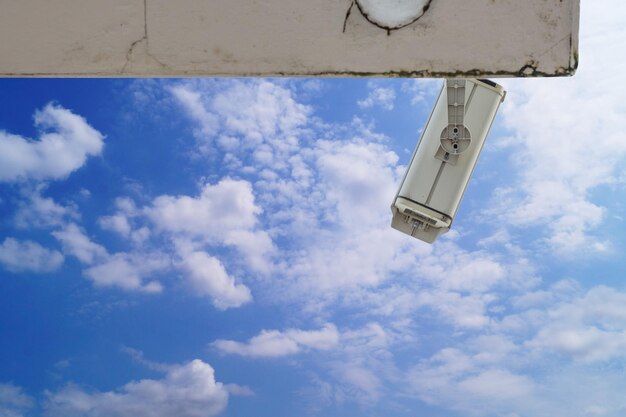 telecamera a circuito chiuso in cima all'edificio su cielo blu e nuvola bianca sullo sfondo