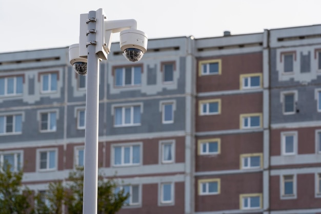 Telecamere CCTV su un palo, la facciata di un condominio a pannelli sullo sfondo