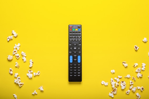 Telecomando nero da TV, sintonizzatore TV o sistema audio su giallo con popcorn