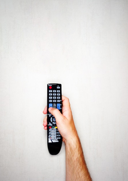 Telecomando nero dalla TV in una mano maschile su uno sfondo grigio chiaro, vista dall&#39;alto