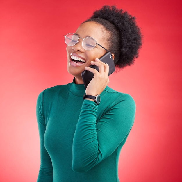 Telefonata di donna felice e ridendo per uno scherzo divertente meme o conversazione contro uno sfondo di studio rosso Persona femminile sorride e ride per una discussione divertente o social media sullo smartphone mobile