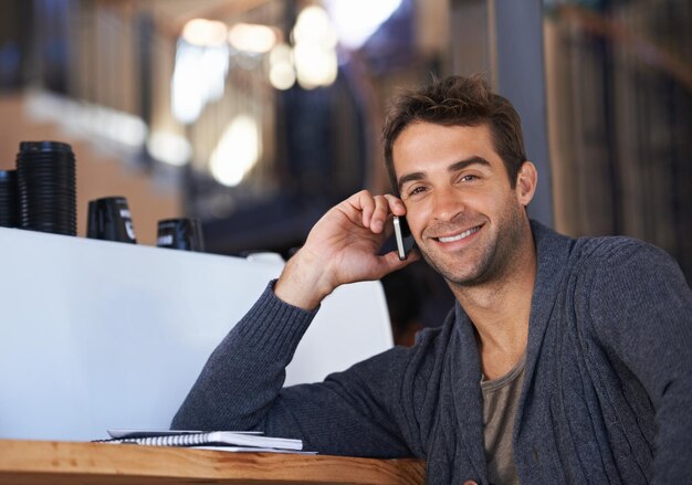 telefonata sorriso e ritratto di un uomo in un caffè per un affare collaborazione o comunicazione di lavoro felice di parlare e giovane uomo sulla conversazione mobile con il cellulare per la carriera in caffè