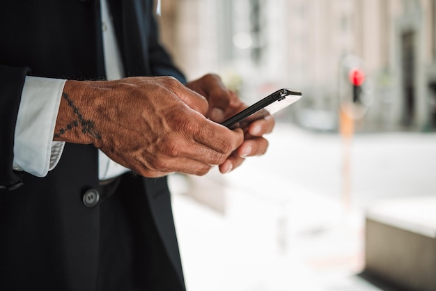 Telefono a mano e navigazione con un uomo d'affari in città usando un'app per cercare una posizione o una direzione Viaggi mobili e comunicazione con un dipendente maschio che scrive un messaggio di testo in primo piano