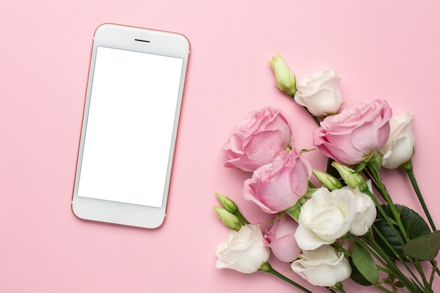 Telefono cellulare con fiori di rose bianche e rosa. Composizione minimalista per le feste, il giorno di San Valentino e il giorno delle donne.
