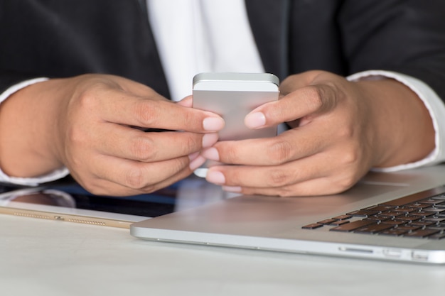 Telefono cellulare della compressa del taccuino delle informazioni di ricerca dell&#39;uomo d&#39;affari all&#39;ufficio.