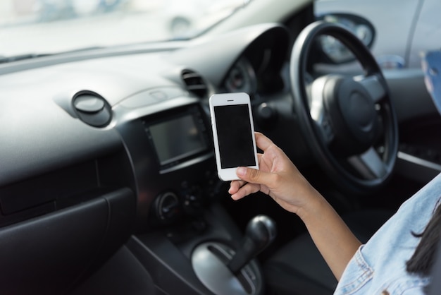 Telefono cellulare della tenuta della donna in automobile