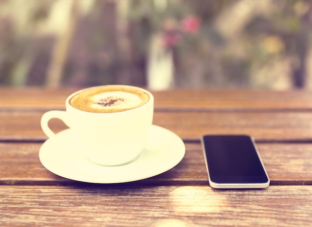 Telefono cellulare e tazza di caffè su un tavolo di legno