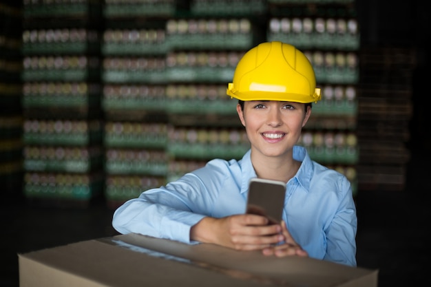 Telefono cellulare femminile della tenuta dell'operaio in fabbrica