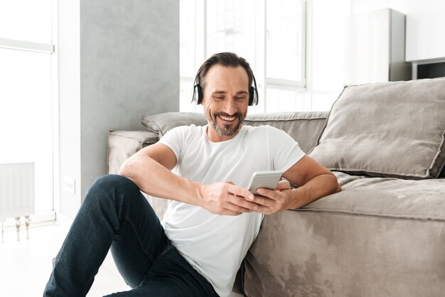 Telefono cellulare maturo felice della tenuta dell'uomo