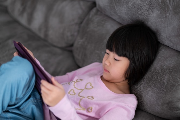 Telefono cinese dipendente da bambini, ragazza asiatica che gioca a smartphone, bambino che guarda un cartone animato