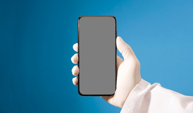 Telefono con mockup di schermo grigio nelle mani di un medico con guanti sanitari