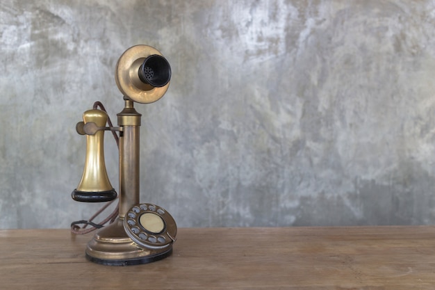 Telefono d&#39;annata sulla tavola di legno con il fondo della parete del cemento, immagine con lo spazio della copia.