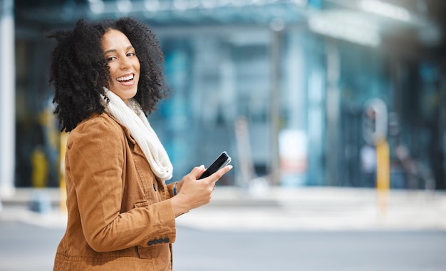 Telefono della città e ritratto di una donna di colore che cammina comunicazione o social media networking sulla strada per il lavoro Viaggia con la tecnologia 5g e la persona della moda invernale sulla chat dello smartphone in strada o strada urbana