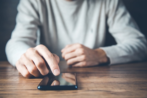 Telefono della mano del giovane sullo scrittorio