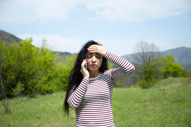 Telefono della mano della donna triste e mano nella testa