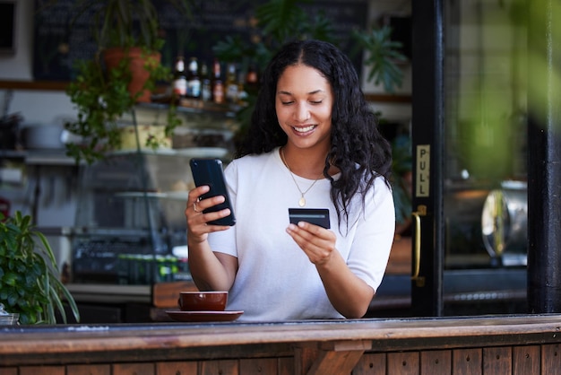 Telefono donna e carta di credito con sorriso per lo shopping online di e-commerce o acquisto presso la caffetteria Felice cliente femminile su smartphone per app di internet banking o transazione wireless al bar