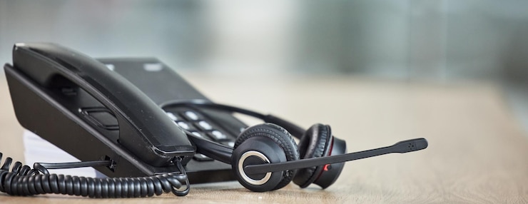 Foto telefono e cuffie del call center per la comunicazione servizio clienti o supporto e-commerce telefonata in agenzia virtuale e sfondo di consulenza per aiutare a contattarci o consulenza e tecnologia