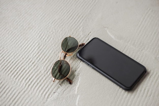 Telefono e occhiali sdraiati sul pavimento di cemento bianco