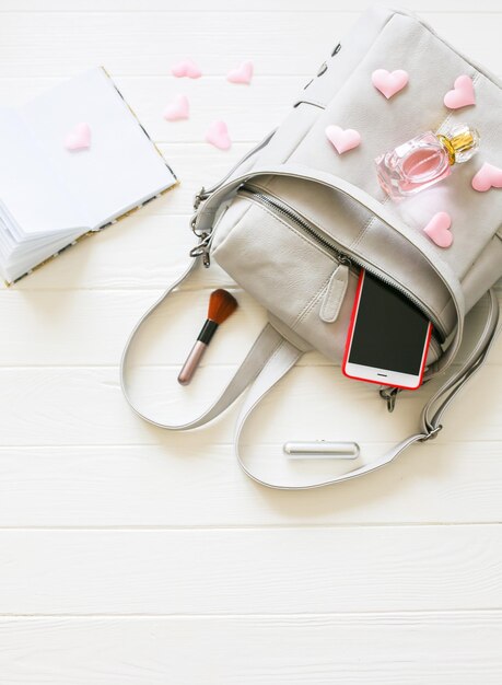 Telefono elegante borsa e profumi su sfondo bianco Bella piatto laici Cose per donna d'affari Programma del taccuino Kit di trucco Regalo della ragazza con i cuori