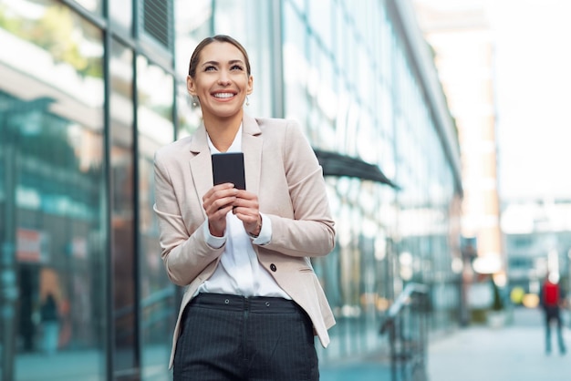 Telefono felice della holding della donna di affari all'aperto