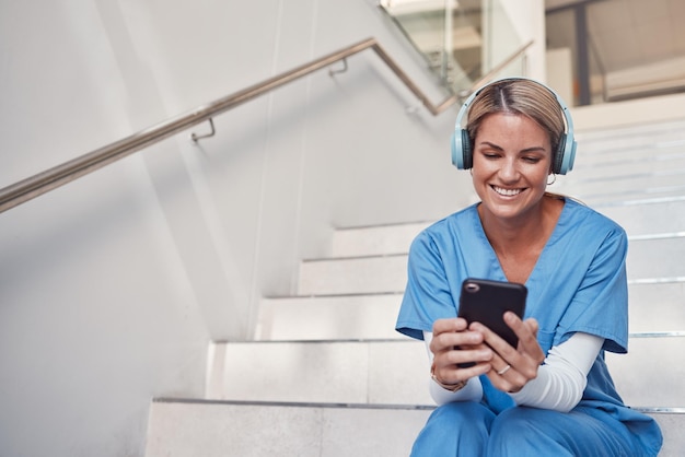 Telefono medico e scale per la comunicazione di consultazione o videochiamata fuori dall'ospedale per consigli sulla salute Infermiera donna felice che sorride nel settore sanitario con smartphone e auricolare per la telemedicina