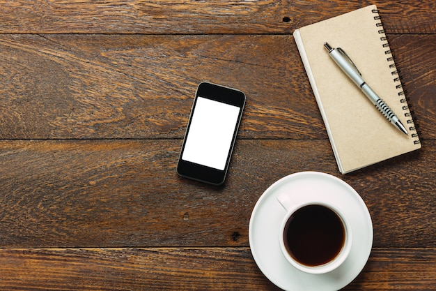 Telefono mobile da tavolo da ufficio, caffè, notebook su legno.
