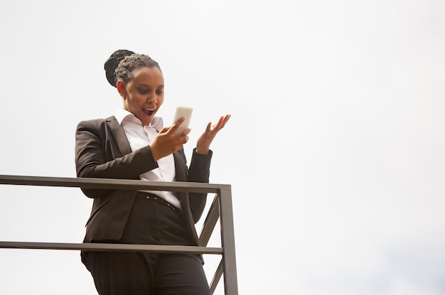 Telefono parlante, vincitore. Donna d'affari afro-americana in abbigliamento da ufficio sorridente, sembra sicura di sé felice, impegnata. Concetto di finanza, affari, uguaglianza e diritti umani. Bella giovane modella, di successo.