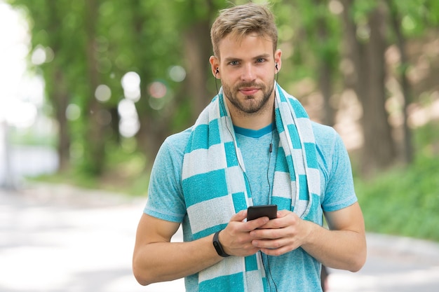 Telefono per il tuo stile di vita attivo. Ragazzo in forma ascolta musica sul telefono cellulare. Utilizzo delle app del telefono per l'allenamento e l'allenamento sportivo. Vita moderna. Nuova tecnologia. Usa il telefono per metterti in forma velocemente.