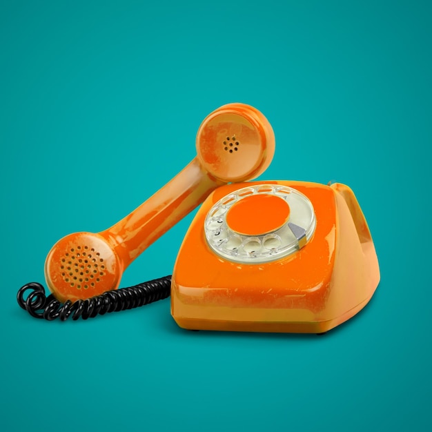 Telefono retro di colore arancione con il portatile sulla scrivania