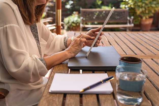 Telelavoro donna dal giardino di casa sua con un tablet.