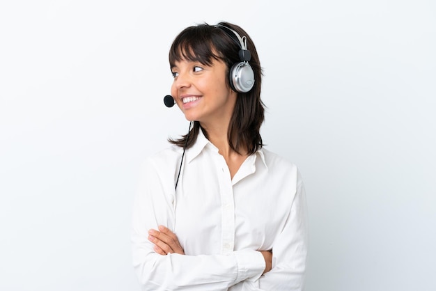 Telemarketer donna di razza mista che lavora con un auricolare isolato su sfondo bianco guardando il lato