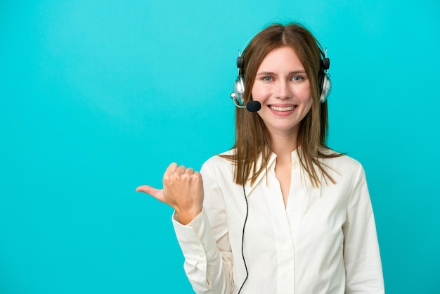 Telemarketer Donna inglese che lavora con un auricolare isolato su sfondo blu che indica il lato per presentare un prodotto