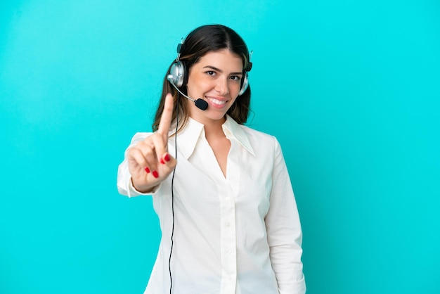 Telemarketer Donna italiana che lavora con un auricolare isolato su sfondo blu che mostra e alza un dito